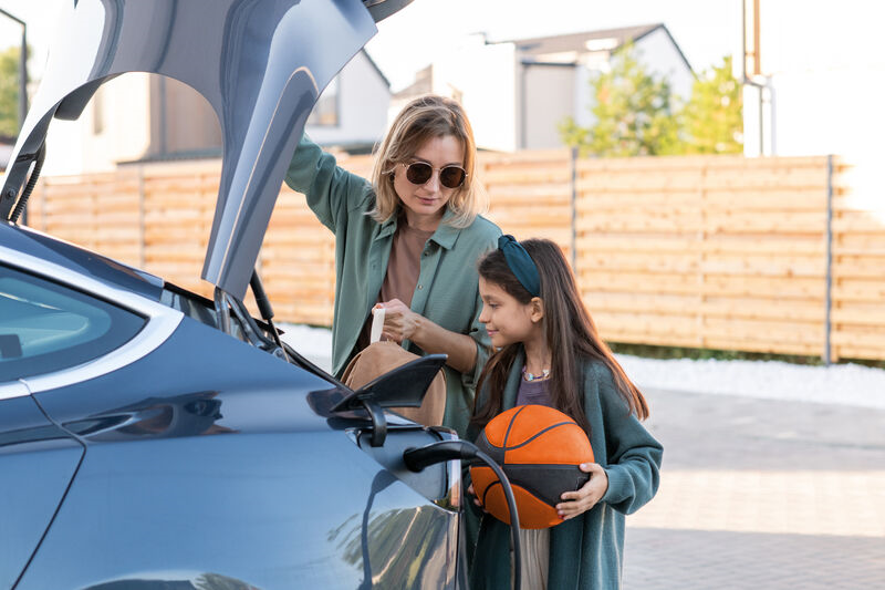 Woman and girl holding boot door open on an EV