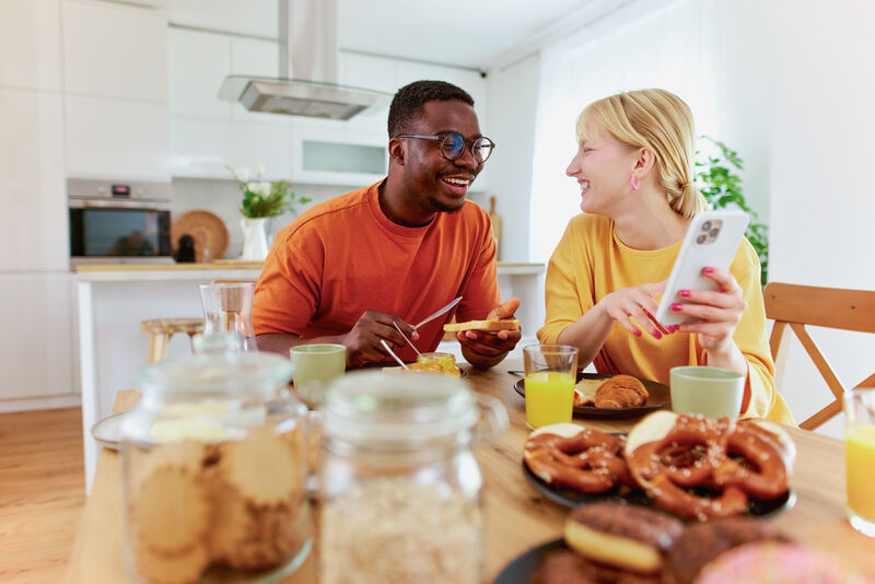 An image of a couple sat at a table, looking at a shared phone