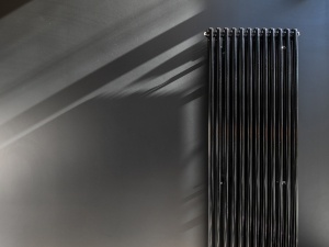 A black vertical radiator on a wall