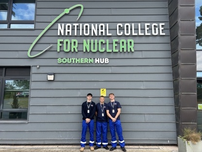 A picture of three young men standing outside a building underneath a sign which reads "National Nuclear College"