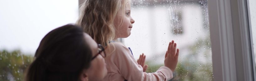 Woman and young girl looking out of a window.