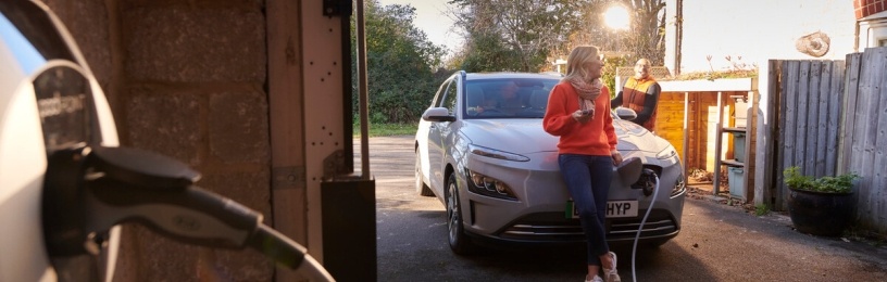 Woman sitting on bonnet of EV whilst it's charging.