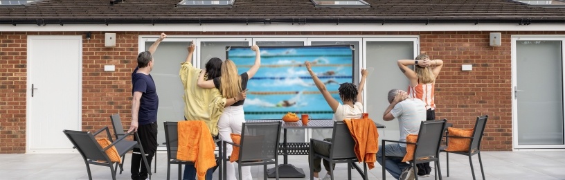 A group of people spectating sports in a garden with solar panels on the roof