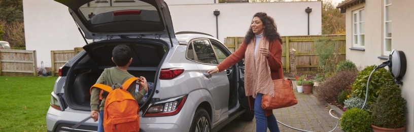 Woman and young boy walking towards electric vehicle.
