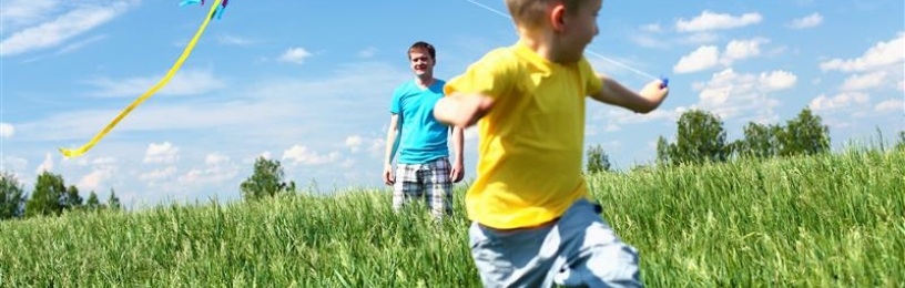 Boy running through field with a kite 