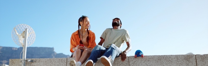Two people sitting on a wall laughing