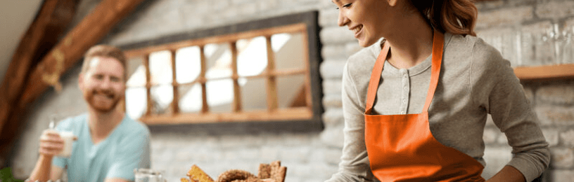 Couple in kitchen with woman cooking looking at a tablet