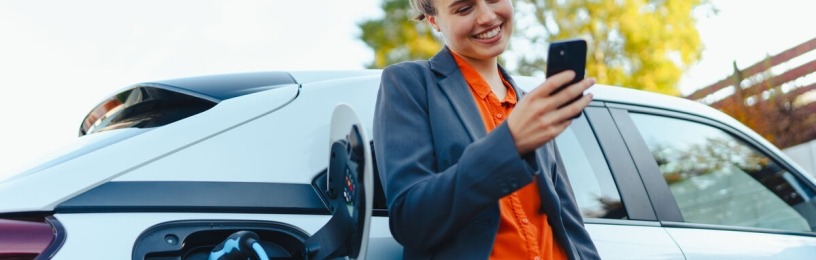 Woman leaning against EV plugged into a charger