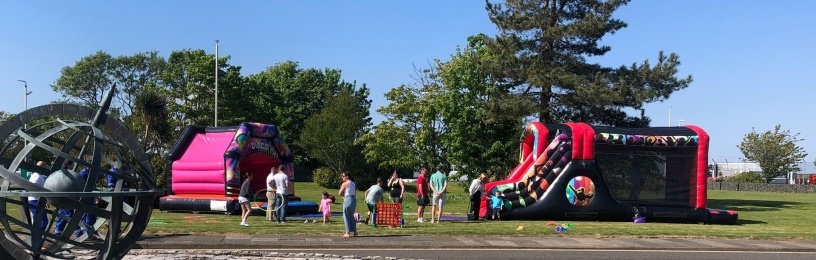 People and bouncy castles on grass on a sunny day