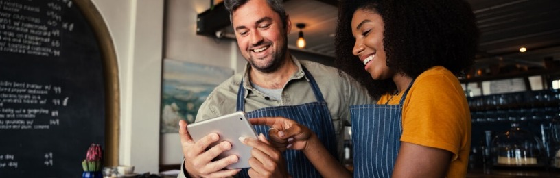Man and woman looking at iPad in coffee shop