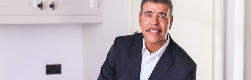 Chris Kamara standing and smiling in a kitchen