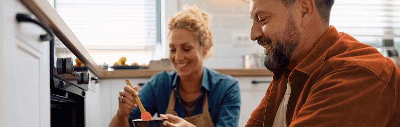 Husband taking roast out of the oven while wife looks on