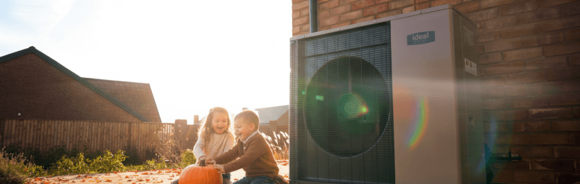 Two children playing in front of a logic air source heat pump