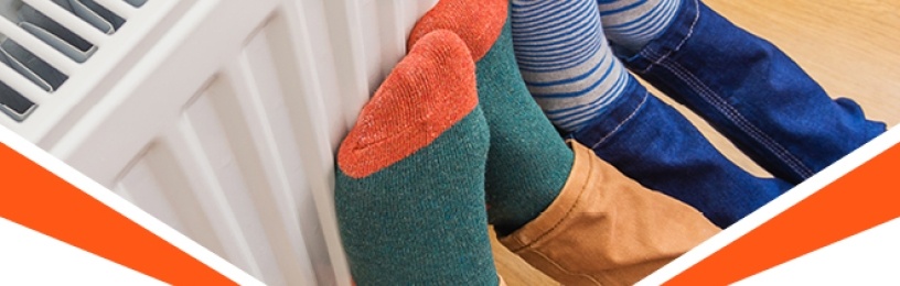 Two pairs of feet in brightly coloured and striped socks lifted up leaning against the radiator to be warmed