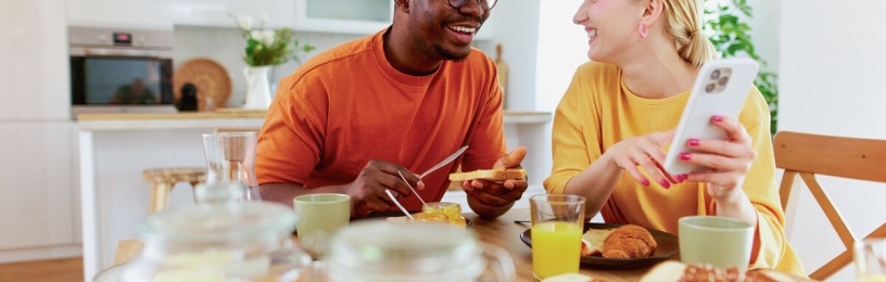Man and woman eating breakfast looking at phone