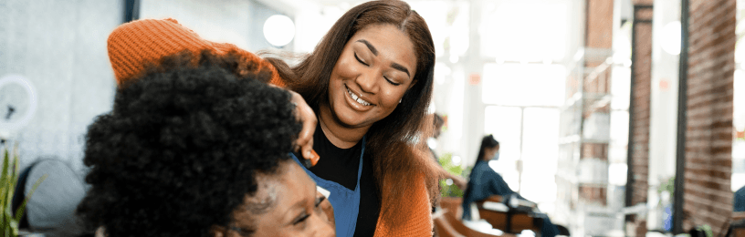 hairdressing salon with customer getting hair cut, happy and smiling, with lady in background