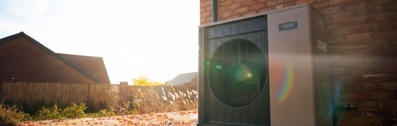 Heat pump on the outside of a house with autumn leaves on the ground