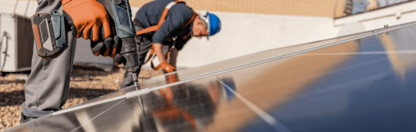 two construction workers drilling solar panels