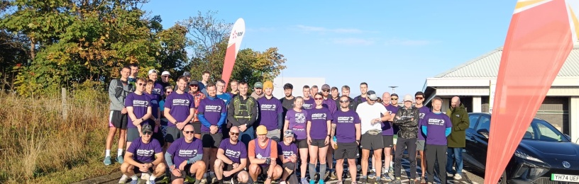 A group of runners wearing Alzheimer Scotland tshirts at the start line of a race.