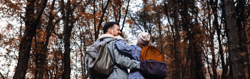 Couple with arms around each other in an autumnal wood 