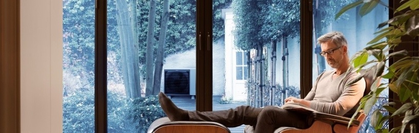 man in his home with air source heat pump outside