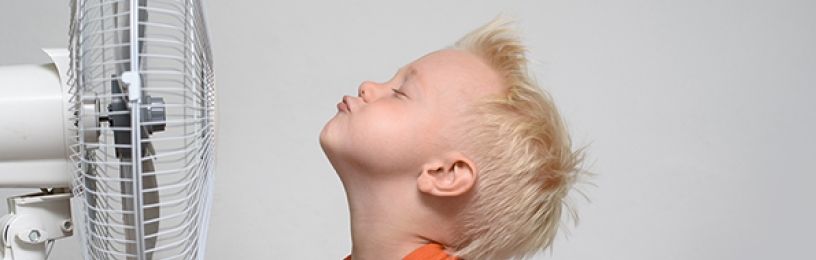 Boy cooling his face with an electric fan