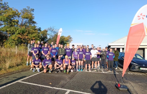 A group of runners wearing Alzheimer Scotland tshirts at the start line of a race.