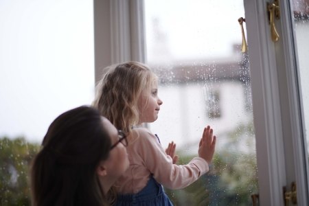 Woman and young girl looking out of a window.