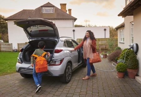 Woman and young boy walking towards electric vehicle.