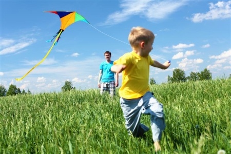 Boy running through field with a kite 