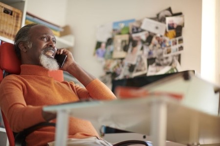 Man in orange jumper speaking on his mobile phone