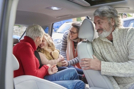 A family in an EV car playing with their child