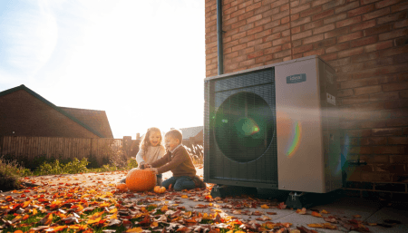 Two children playing in front of a logic air source heat pump
