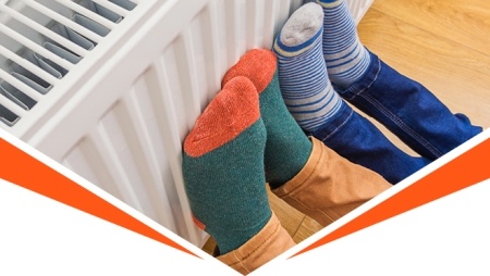Two pairs of feet in brightly coloured and striped socks lifted up leaning against the radiator to be warmed