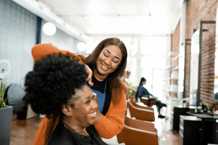 hairdressing salon with customer getting hair cut, happy and smiling, with lady in background
