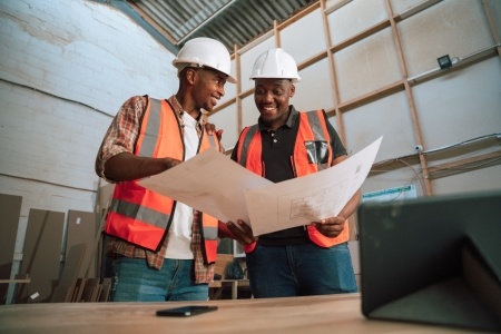 Two people looking at plans in hard hats and high vis