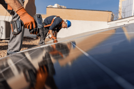 two construction workers drilling solar panels