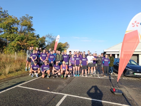 A group of runners wearing Alzheimer Scotland tshirts at the start line of a race.