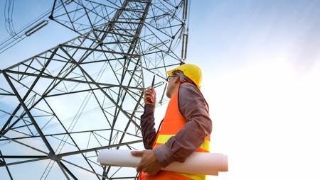 Engineer looking up at a electricity pylon