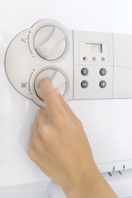 Person turning down heating flow temperature on boiler