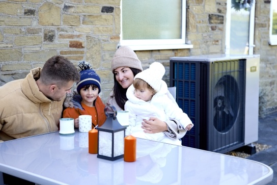 Family of four sitting outside near an Ideal air source heat pump 