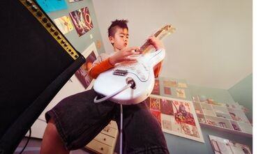 Boy playing white electric guitar