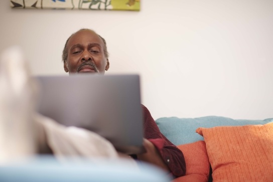Man sitting on a sofa looking at his laptop