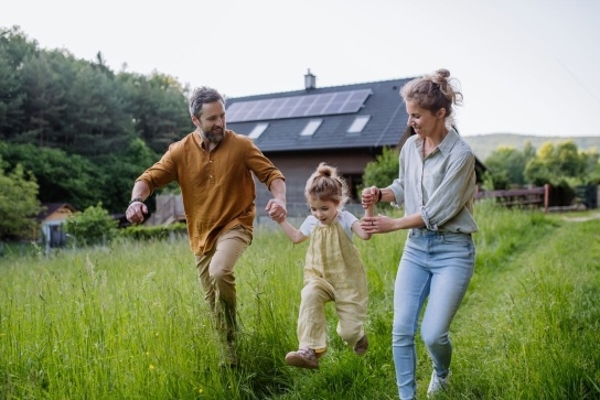 Family running in garden with house with solar panels in the background