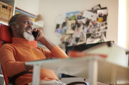Man in orange jumper speaking on his mobile phone