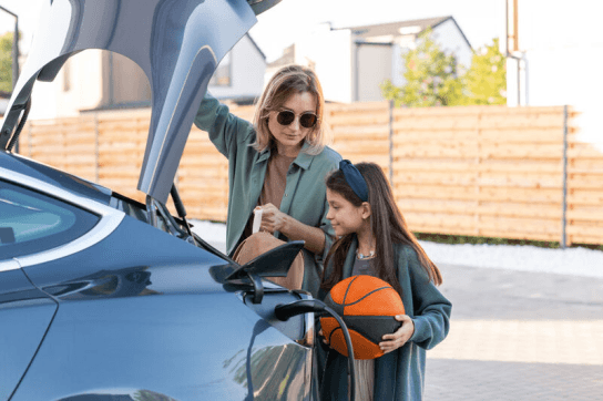 Woman and girl holding boot door open on an EV