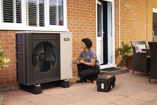Air source heat pump installer kneeling beside an Ideal air source heat pump 