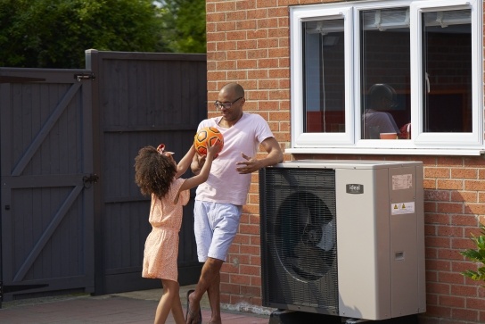Father and daughter playing next to air source heat pump