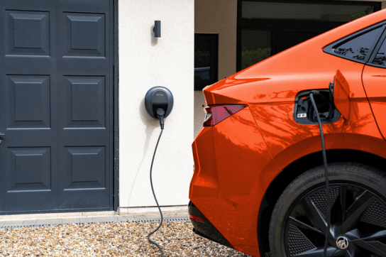 Orange EV charging with a Pod Point Solo 3S tethered to a wall mount outside the garage