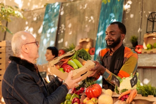 Man passing customer fruit at fruit stall 